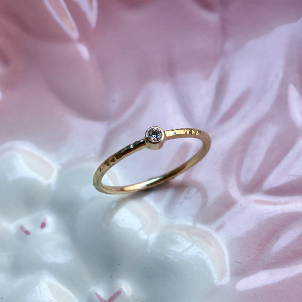 Smuk klassisk ring med rund ringskinne og en rørfatning med en lys champagnefarvet naturlig diamant. Ringen har fået en struktureret overflade, som er håndlavet med filestrøg, og derefter blankpoleret. 