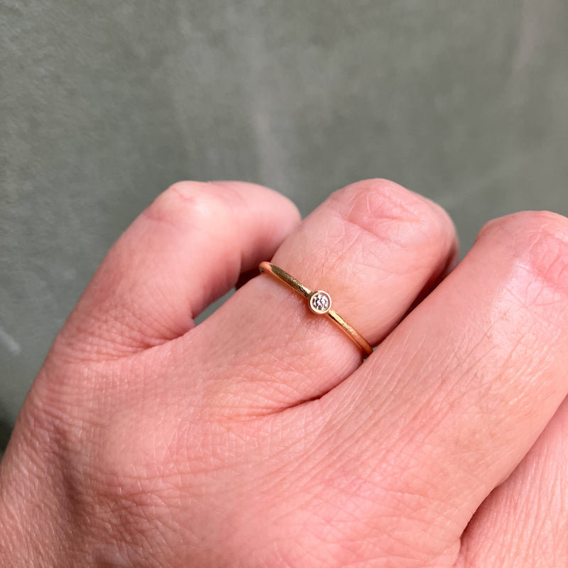 Smuk klassisk ring med rund ringskinne og en rørfatning med en lys champagnefarvet naturlig diamant. Ringen har fået en struktureret overflade, som er håndlavet med filestrøg, og derefter blankpoleret. 