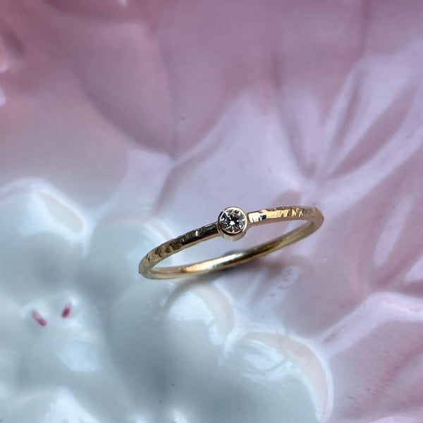 Smuk klassisk ring med rund ringskinne og en rørfatning med en lys champagnefarvet naturlig diamant. Ringen har fået en struktureret overflade, som er håndlavet med filestrøg, og derefter blankpoleret. 