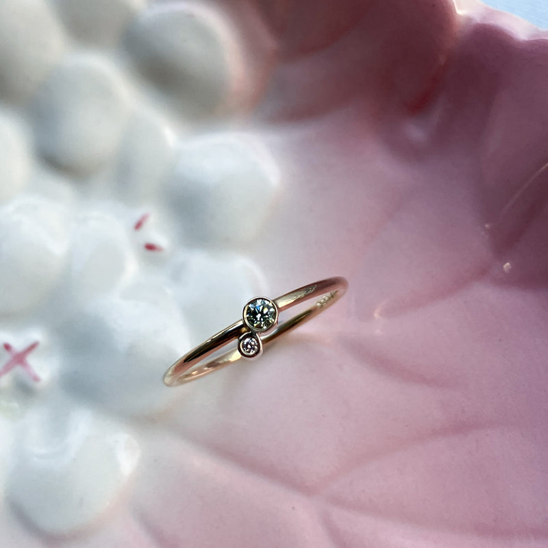 En lækker klassisk ring med en rund ringskinne i 14 karat guld, håndlavet med to fine rørfatninger og en champagne diamant og en grøn diamant. Blankpoleret overflade 