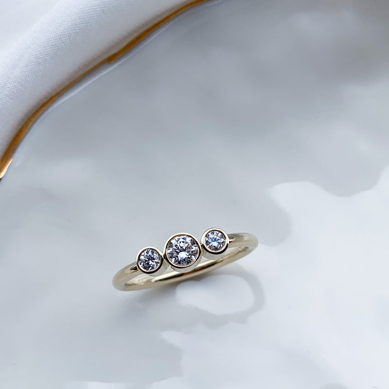 Klassisk 3 stens ring i 14 karat gult guld lavet med smukke enkle rørfatninger med hvide diamanter, og en rund ringskinne i blankpoleret guld. Klassisk forlovelsesring