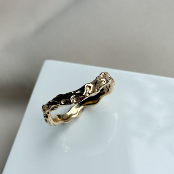 Organisk ring med lækre detaljer i det blankpolerede guld. Ringen har en let kurvet facon, og den organiske overflade gør at lyset blinker smukt i ringen.