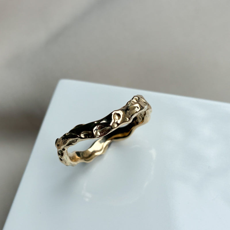 Organisk ring med lækre detaljer i det blankpolerede guld. Ringen har en let kurvet facon, og den organiske overflade gør at lyset blinker smukt i ringen.