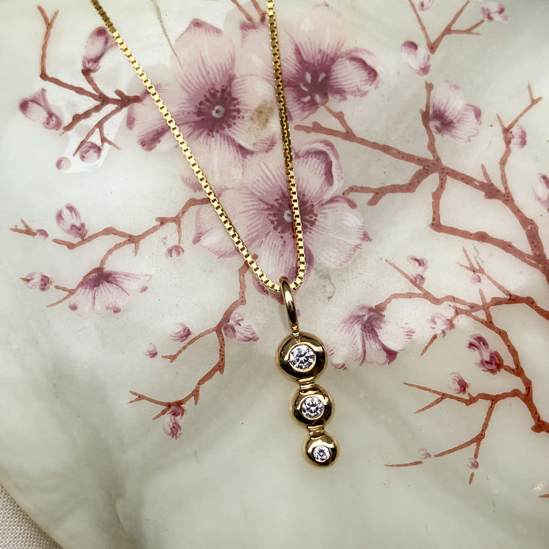 Vedhaeng i 14 karat gult guld med 3 kugler o forskellig stoerrelse. Der sidder tre diamanter i hver sin kugle